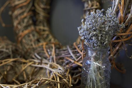 Textured Christmas wreath made from woven vine branches, black candles and dry lavender in glass vase, selective focusの写真素材
