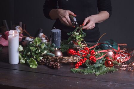 Close up of a female florist making a Christmas wreath of fir branches, Christmas bubbles and natural decor, selective focusの写真素材