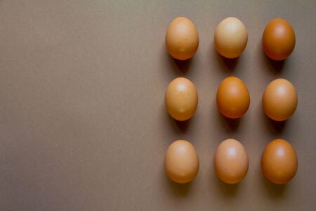 Nine brown chicken eggs on brown backdrop, minimalistic food or easter conceptの写真素材