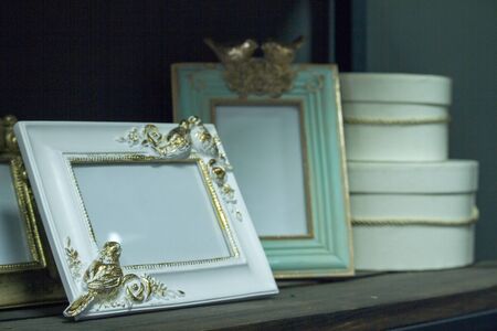 Close up wooden shelf with vintage frames and hat boxes, selective focus