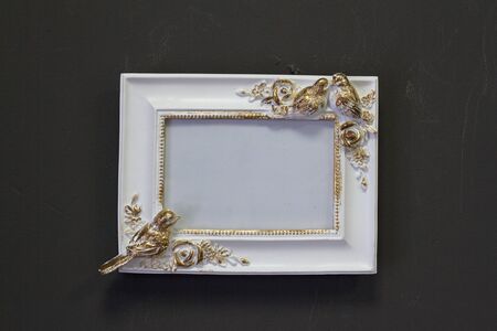 Empty white gold vintage square frame in Victorian style on a gray wall, background or concept
