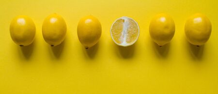 Top view whole and sliced ripe lemon slaid out in a row on yellow surface, concept of health and...