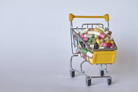 Medical background or concept. Close-up of shopping trolley filled with colorful pills. Cart from...
