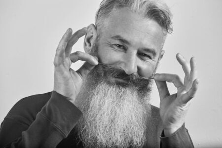 Black and white portrait of mature gray-haired bearded man in blue sweatshirt on grey background, selective focusの写真素材