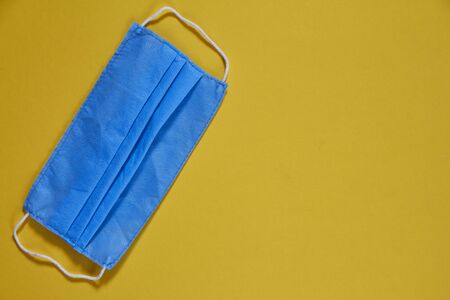 Face mask for protecting against corona virus, blue medical mask on yellow background, surgical mask used against pollution, viruses and fluの写真素材