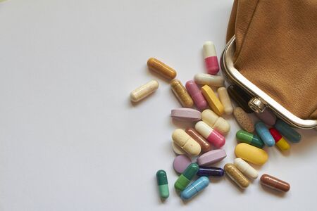 Multi-colored pills and capsules spill out of small wallet