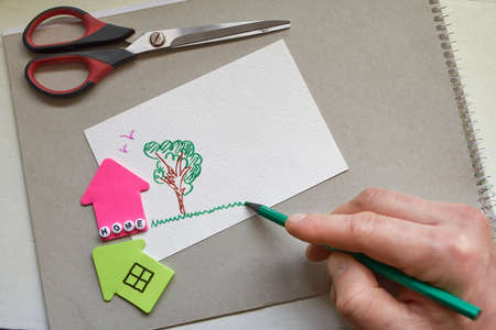 Two paper houses with word Home made of letters and male hand draws tree and grass. Stay Home picture. Coronavirus concept.の写真素材