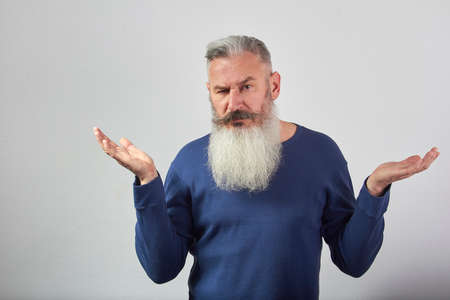 Portrait of indignant mature gray-haired bearded man on grey background, selective focusの写真素材