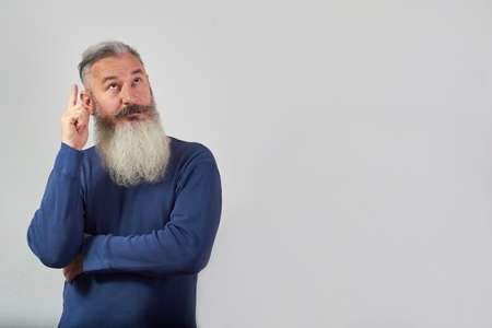 I have an idea concept, portrait of mature gray-haired bearded man on grey background, selective focusの写真素材
