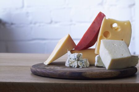 Food background, various types of cheese composition on wooden cutting board, selective focusの写真素材