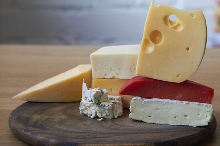 Food background, various types of cheese composition on wooden cutting board, selective focusの写真素材