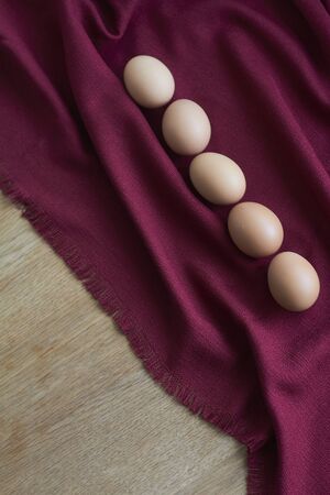 Natural eggs on red tablecloth, few brown chicken eggs lie on burgundy tablecloth, selective focusの写真素材