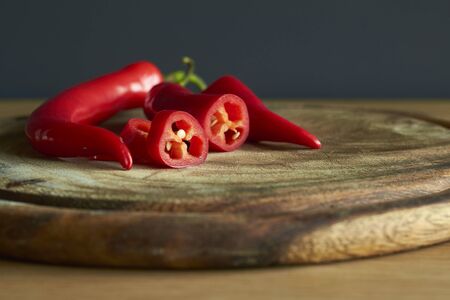 Close up of sliced red hot chili peppers on wooden cutting board, selective focus