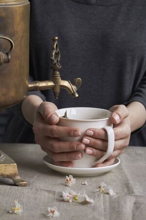 Side view of female hands pour cup of tea from vintage samovar and jar of homemade jam, tea party conceptの写真素材