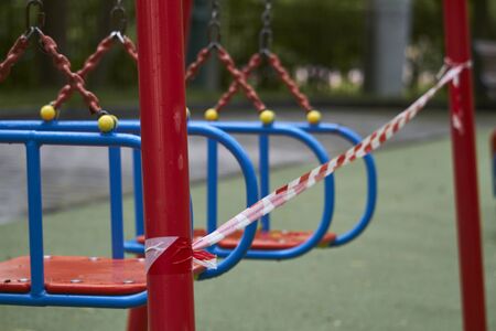Empty playground without children with striped red and white warning tape, limitations quarantined for Covid19 coronavirusの写真素材