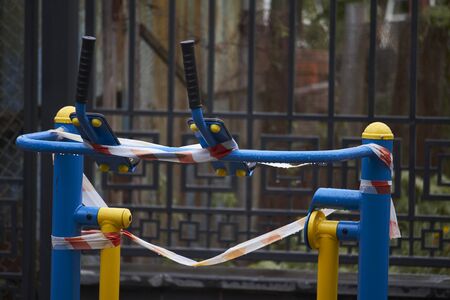 An empty outdoor fitness equipment wrapped with warning red and white tape during quarantine period of COVID-19の写真素材