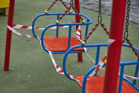 Empty playground without children with striped red and white warning tape, limitations quarantined for Covid19 coronavirusの写真素材