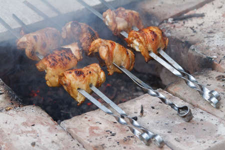 Close up of chicken legs strung on skewers and fried over an open fire, selective focusの写真素材