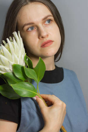 Portrait of brunette girl holds white huge protea, selective focus