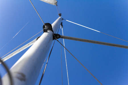 Bottom view of mast and sail of yacht on blue sky backdrop, selective focusの写真素材