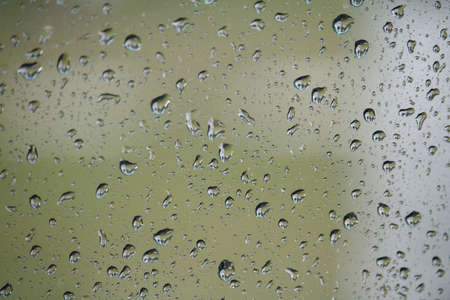 Close up of glass with raindrops on natural background, drops of water on car glass, selective focusの写真素材