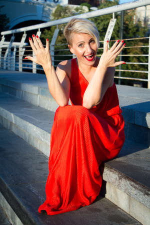 Happy beautiful woman in red dress with various emotions close up portraitの写真素材