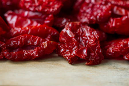 Close up sundried tomatoes with spices and olive oil on wooden cutting board, background or concept, selective focusの写真素材