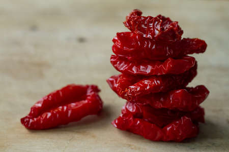 Close-up sun-dried tomatoes with spices and olive oil on wooden cutting board, background or concept, selective focusの写真素材