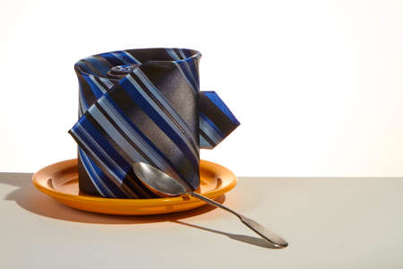 Business breakfast concept, tie instead of cup on saucer and teaspoon, selective focusの写真素材