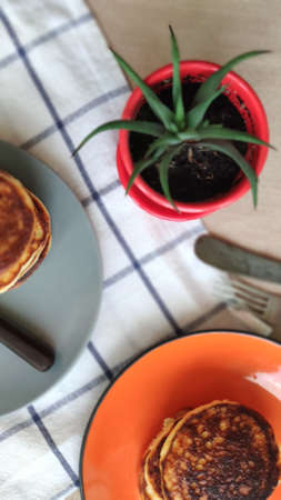 Plate with stack of homemade pancakes and cactus in red pot, selective focusの写真素材