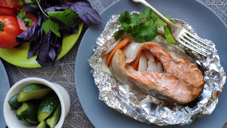 Top view of homemade foil baked salmon steak and fresh vegetables, selective focusの写真素材