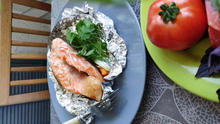 Top view of homemade foil baked salmon steak and fresh vegetables, selective focusの写真素材