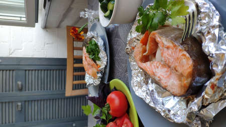 Homemade foil baked salmon steak with herbs, home cooking concept, selective focusの写真素材