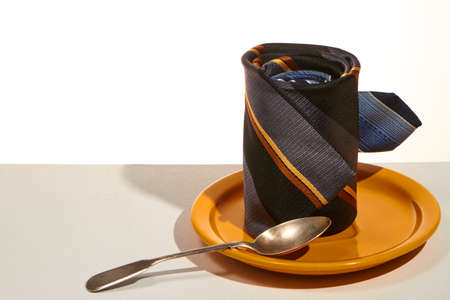 Business breakfast concept, tie instead cup on saucer and teaspoon, selective focusの写真素材