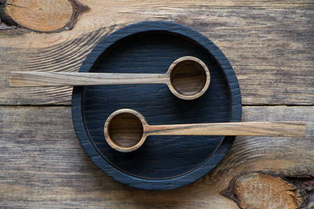 Top view two wooden spoons on black plate on wooden table, eco friendly cutlery concept, selective focusの写真素材