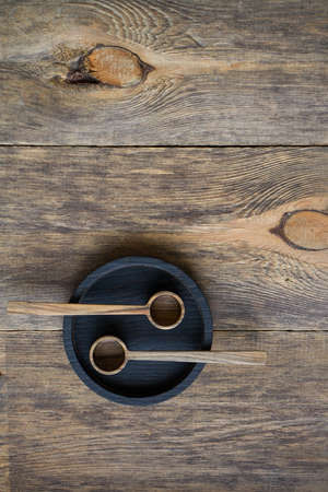 Top view two wooden spoons on black plate on wooden table, eco friendly cutlery concept, selective focusの写真素材