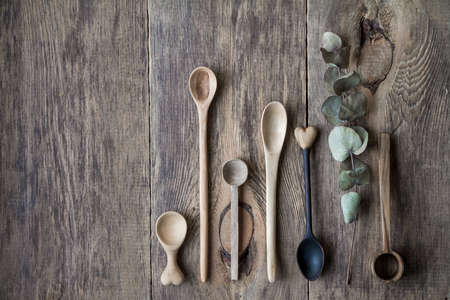 Top view few wooden spoons and eucalyptus branch on wooden table, eco friendly concept of cutlery, handmade tableware productionの写真素材