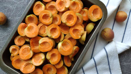 Lot of orange sweet apricots in baking sheet on striped kitchen towel, selective focusの写真素材