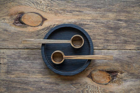 Top view two wooden spoons on black plate on wooden table, eco friendly cutlery concept, selective focusの写真素材