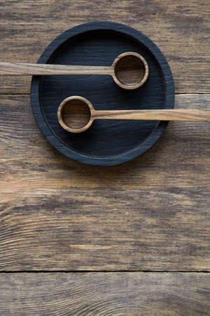 Top view two wooden spoons on black plate on wooden table, eco friendly cutlery concept, selective focusの写真素材