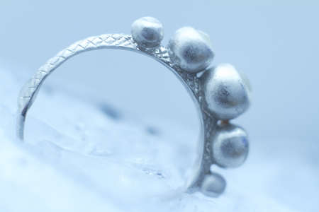 Close-up silver ring frozen into ice on white background, selective focusの写真素材