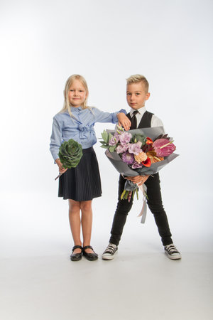Studio portrait boy gives girl festive bouquet, congratulatory concept, white background, copy spaceの写真素材