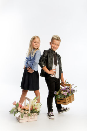 Studio portrait boy and girl dressed school uniform with greeting flower arrangements in wooden baskets, congratulatory concept, white background, copy spaceの写真素材