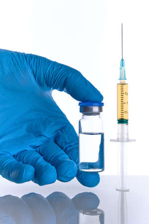 Male doctor hand in blue glove holds syringe and vial bottle with c vaccine drug multiple injections dose. cure, flu medicine treatment vaccination concept.の写真素材