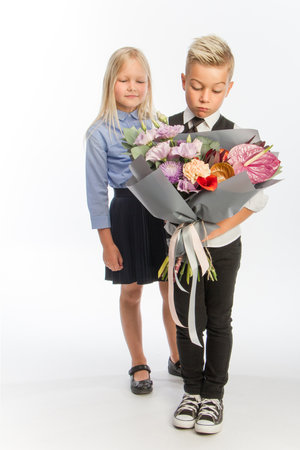 Studio portrait boy gives girl festive bouquet, congratulatory concept, white background, copy spaceの写真素材