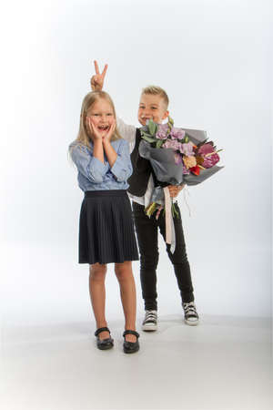Studio portrait boy gives girl festive bouquet, congratulatory concept, white background, copy spaceの写真素材
