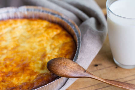 Cottage cheese casserole with glass of milk on wooden table background. Cottage cheese casserole.の写真素材