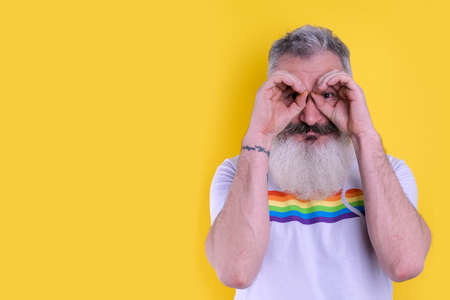 Confident mature bearded man dressed with  symbols t-shirt looking at camera, studio portrait of  man, yellow backgroundの写真素材
