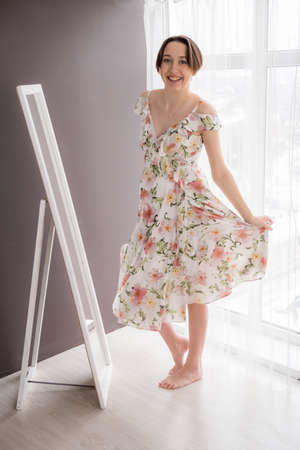 Young adult pregnant girl dressing up and having fun over mirror in bright modern bedroom, selective focusの写真素材