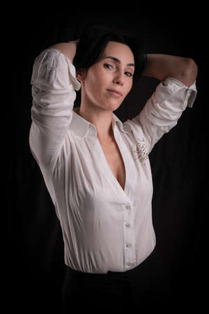 Portrait of beautiful mature brunette woman dressed in white shirt isolated on black backdrop, copy spaceの写真素材